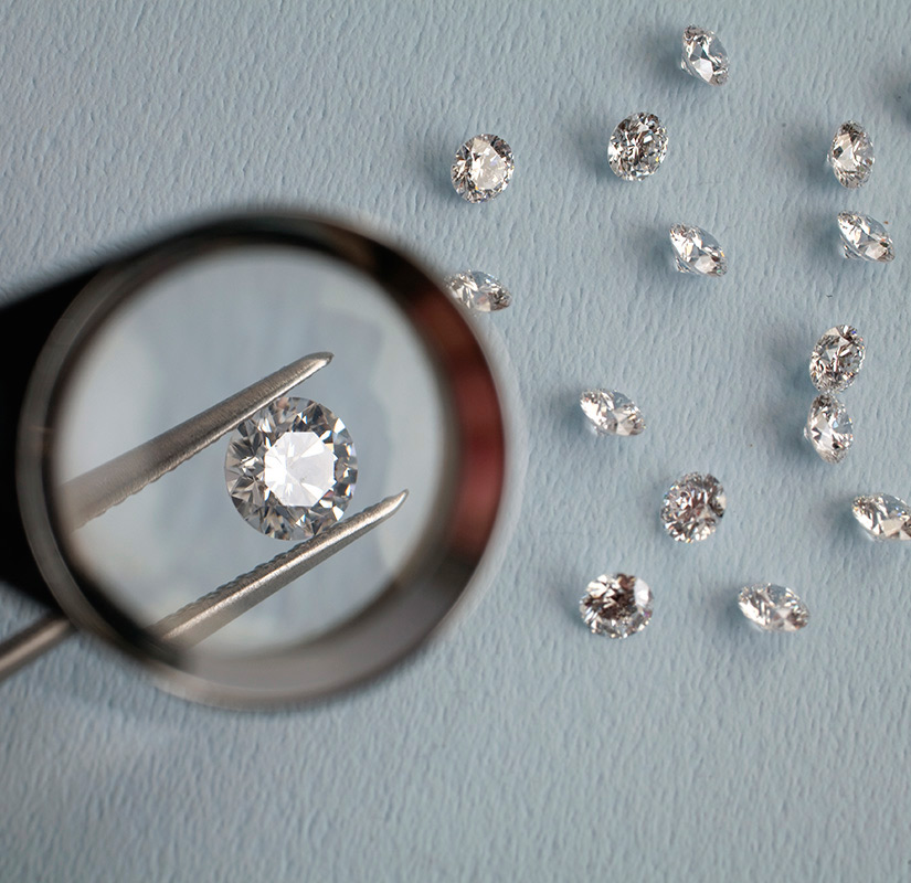 Ideal Cut Diamond Under Magnifying Glass with Assortment of Diamonds on the Table