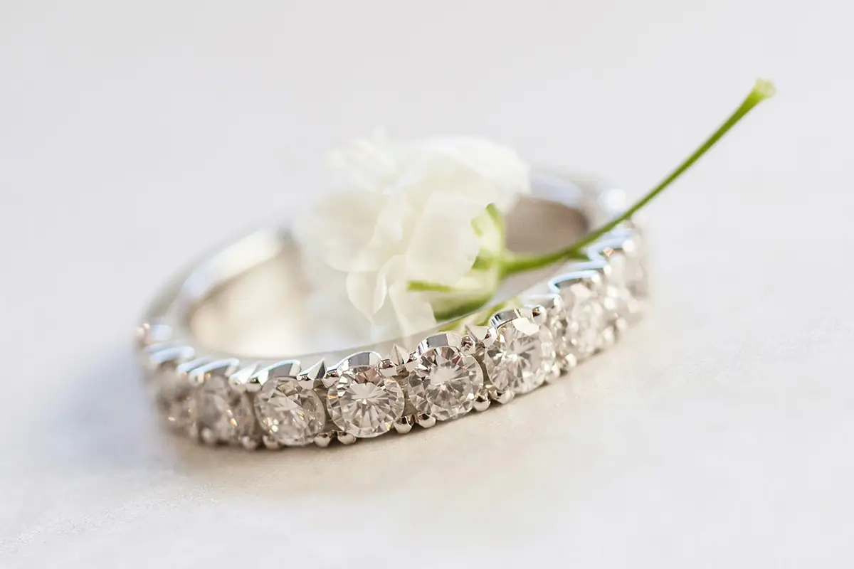 Silver ring with diamonds with white flower in it.